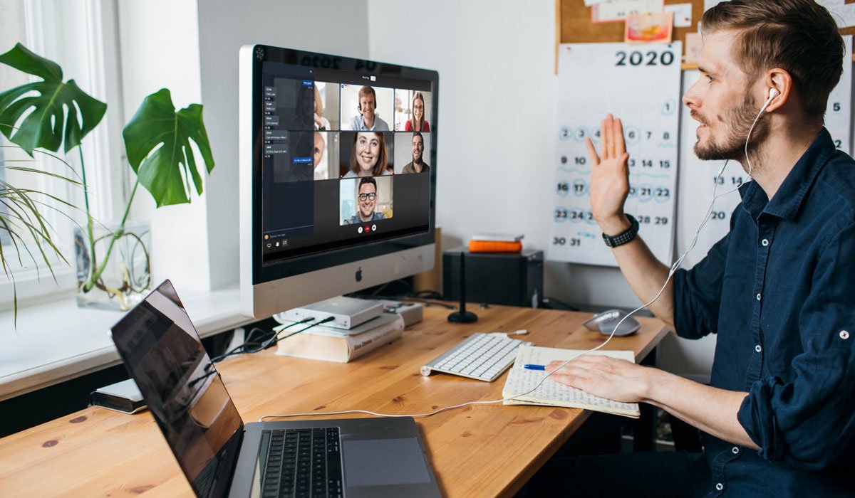 man working from home using screenshare waving at computer