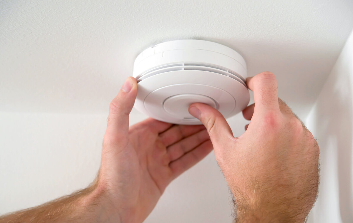 Man installing fire alarm on ceiling