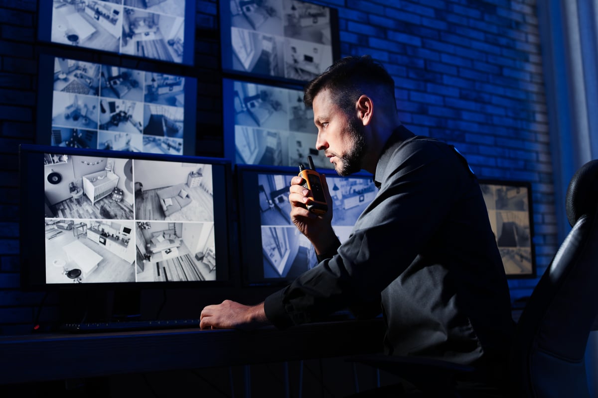 Security worker using walkie talkie to communicate with team in dark security room