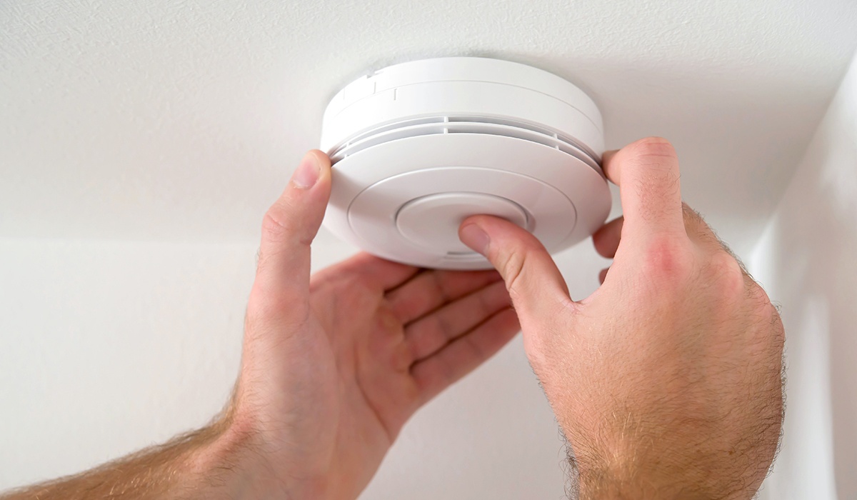 Person installing smoke detector on ceiling