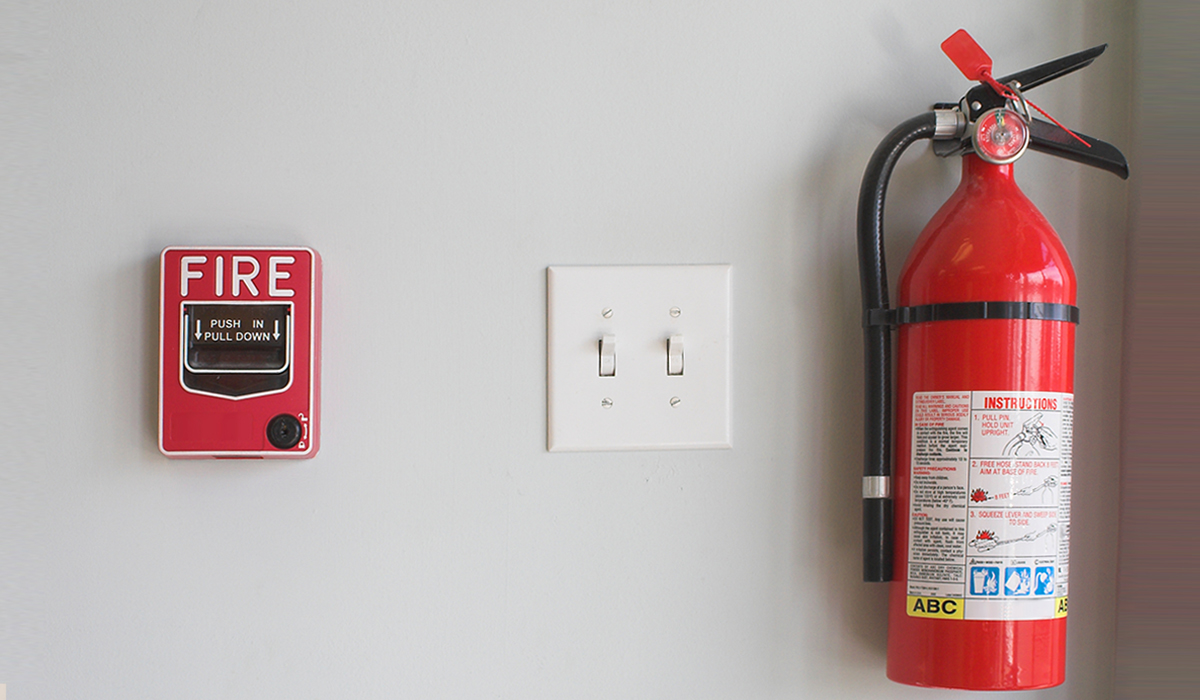 Fire extinguisher next to light switch next to fire alarm