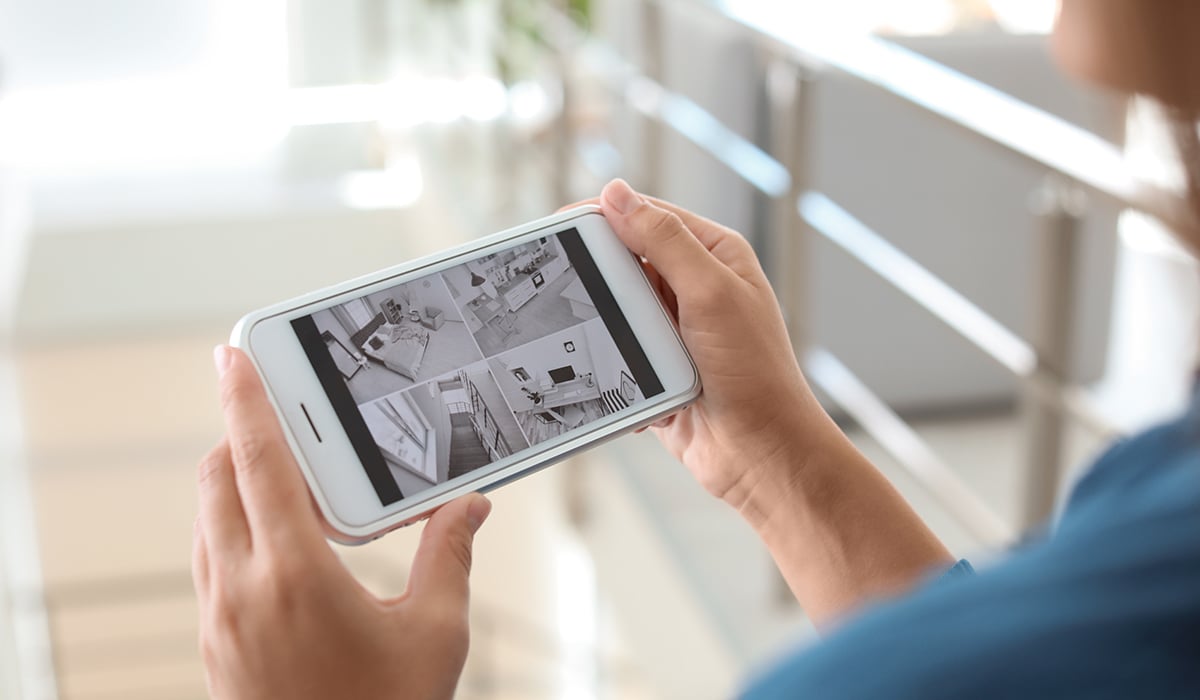 Phone user looking at security camera feed on smartphone