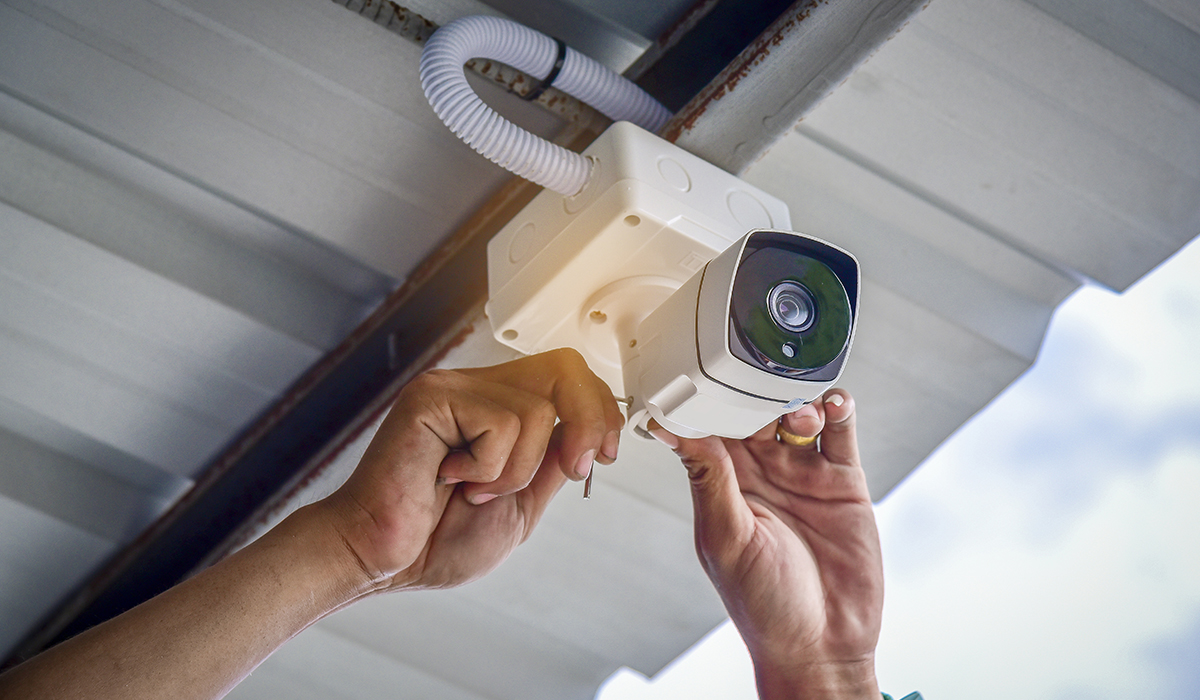Technician installing CCTV Camera under roof overhang