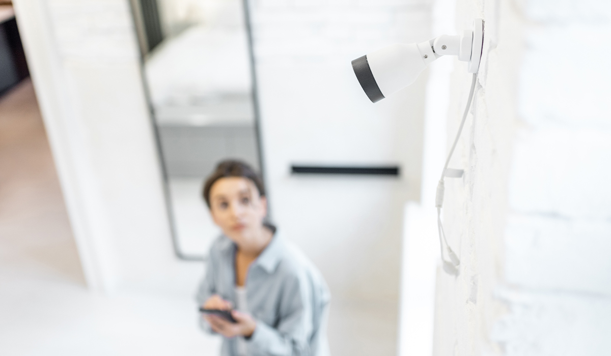 Woman in home looking up at security camera in corner of house